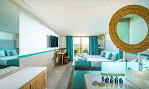 Et moderne hotellrom med dobbeltseng, blå detaljer og en stor vindu mot balkongen. (AI-generert tekst)