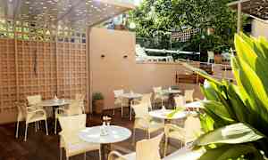 En terrasse med bord og stoler, omgitt av grøntområder. (AI-generert tekst)