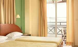 Et hotellrom med to enkeltsenger, gardiner og en balkong. (AI-generert tekst)