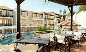 Hotellbygning med balkonger og parasoller ved bassenget, med sittegrupper i forgrunnen. (AI-generert tekst)