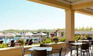 Utendørs servering med stoler og bord, med utsikt mot et basseng og solsenger. (AI-generert tekst)