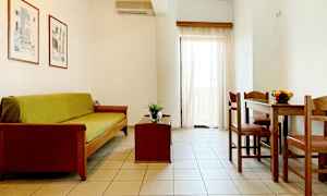 En stue med sofa, sofabord og spisebord med stoler. Lyse vegger og gardiner. (AI-generert tekst)