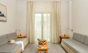 En stue med to grå sofaer, et bord med fruktkurv og en bok, samt gardiner foran vinduet. (AI-generert tekst)