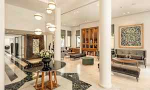 Moderne designet hotellobby med marmorgulv, lyse møbler og hengende lamper. (AI-generert tekst)