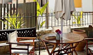 En uteplass med bord, stoler og parasoll. (AI-generert tekst)