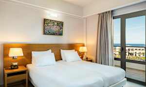 Et rom med to enkeltsenger, bordlamper og en vindusdør som vender mot sjøen. (AI-generert tekst)