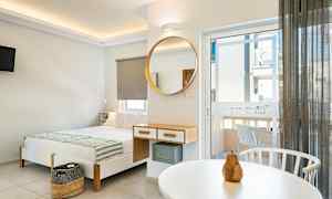 Moderne innredet hotellrom med seng, speil og balkongdør. (AI-generert tekst)