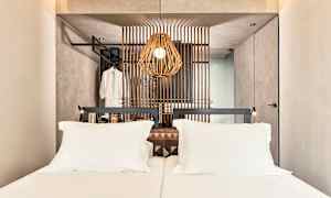 Et hotellrom med en dobbeltseng og en dekorativ trepanel bak sengen. (AI-generert tekst)