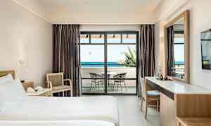 Hotellrom med seng, skrivebord og balkong med havutsikt. (AI-generert tekst)