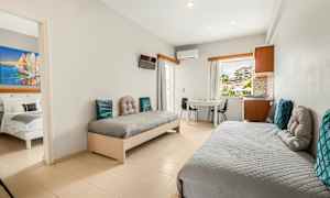 Et hotellrom med to enkeltsenger, et bord og stoler, samt utsikt gjennom vinduet. (AI-generert tekst)