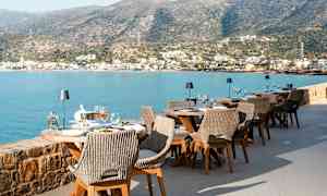 Utendørs servering ved sjøen med utsikt over fjellene og en by. (AI-generert tekst)