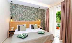 Soverom med dobbeltseng, grønne puter og dekorert vegg. (AI-generert tekst)