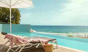 Solstoler ved et basseng med havutsikt. (AI-generert tekst)