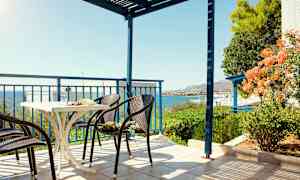 En terrasse med stoler og et bord, havutsikt og grøntområder. (AI-generert tekst)