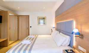 Et hotellrom med en dobbeltseng, tredetaljer, blå lamper og et speilskap. (AI-generert tekst)