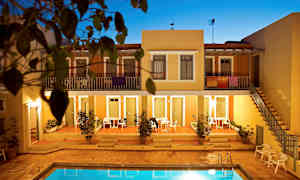 Leilighetskompleks med et basseng i forgrunnen, omgitt av terrakottafargede bygninger og vegetasjon. (AI-generert tekst)