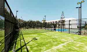 En utendørs belyst padelbane med et nett mellom spilleområdene. (AI-generert tekst)