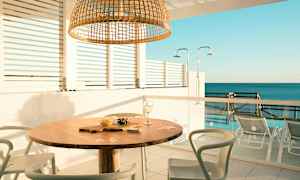 Utendørsområde med bord og stoler, havutsikt i bakgrunnen. (AI-generert tekst)