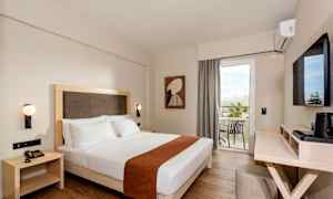 Hotellrom med en dobbeltseng, vegghengte lamper og en balkong med utsikt. (AI-generert tekst)