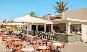 Utendørs restaurant med bar og sitteplasser under parasoller. (AI-generert tekst)