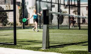 Padelbane med nett og spillere i bakgrunnen. (AI-generert tekst)