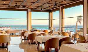 En elegant restaurant innendørs med store vinduer og havutsikt. (AI-generert tekst)