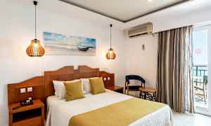 Et hotellrom med en dobbeltseng, to nattbord med lamper og en stol ved siden av et bord. (AI-generert tekst)