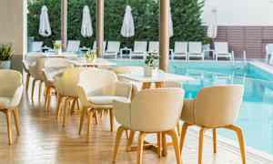 Uteservering ved basseng med stoler og bord. (AI-generert tekst)