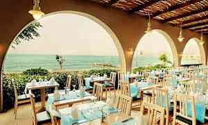 Restaurant med dekkede bord og utsikt over havet gjennom buer. (AI-generert tekst)