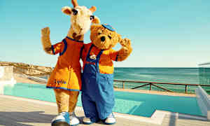 To maskoter, en giraff og en bjørn, står ved et basseng og vinket. (AI-generert tekst)