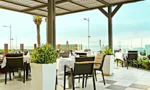 Utendørsrestaurant med havutsikt. (AI-generert tekst)