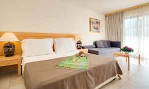 Hotellrom med dobbeltseng, sofa og bord. (AI-generert tekst)