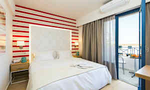 Et hotellrom med en seng, nattbord og åpen balkongdør. (AI-generert tekst)