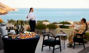 Bord med forretter og drikker, i bakgrunnen havutsikt. (AI-generert tekst)