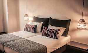 Et soverom med en dobbeltseng, pynteputer og hengende lamper. (AI-generert tekst)