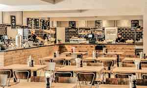 Spiseområde med tremøbler og en serveringsdisk i bakgrunnen. (AI-generert tekst)