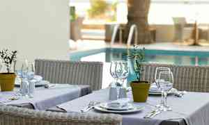 Et dekket bord med hvite tallerkener og glass, plassert ved et basseng. (AI-generert tekst)