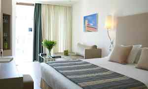 Et moderne hotellrom med en stor seng, skrivebord og en komfortabel sitteplass i lyse farger. (AI-generert tekst)