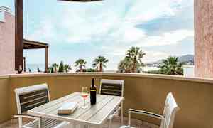 Utsikt fra en terrasse med bord og stoler, vinflaske og glass. (AI-generert tekst)