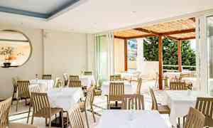 Restaurant med spisebord og stoler, utsikt mot en terrasse. (AI-generert tekst)