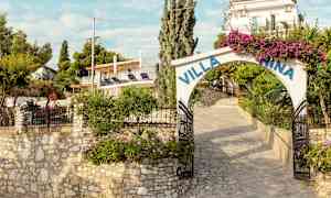 En steinlagt inngang til Villa Nina med blomster og grønt rundt. (AI-generert tekst)