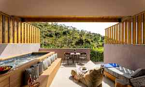 En uteplass med boblebad, sitteplasser og utsikt over grønn natur. (AI-generert tekst)