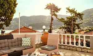 En terrasse med sofagruppe og utsikt over tak og fjell. (AI-generert tekst)