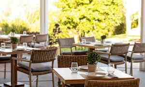 Et luftig område med bord og stoler, dekorert med små planter og serveringsoppsett. (AI-generert tekst)