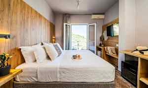 Hotellrom med en dobbeltseng, dekorert med trepaneler og en balkong med utsikt. (AI-generert tekst)