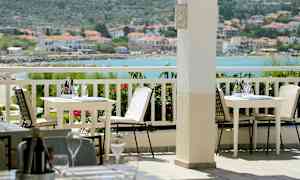 Utendørs terrasse med bord og stoler, med havutsikt i bakgrunnen. (AI-generert tekst)