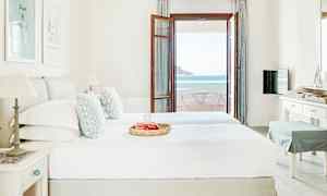 Et hotellrom med en dobbeltseng, innredet i lyse farger, og en verandadør som leder ut til en balkong med havutsikt. (AI-generert tekst)