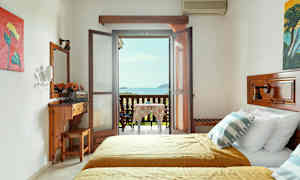 Et hotellrom med to senger og en møblert balkong med utsikt over havet. (AI-generert tekst)