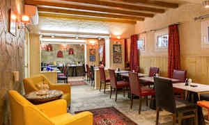 En restaurant med trebjelker i taket og bord omgitt av røde og svarte stoler. (AI-generert tekst)