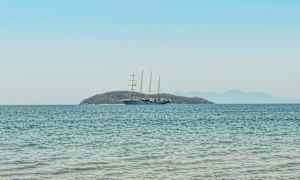 En seilbåt på åpent vann med en øy i bakgrunnen. (AI-generert tekst)